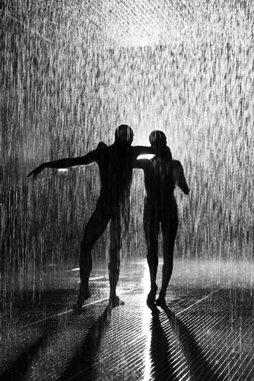 Dancers silhouetted in the artifical drizzle of the Rain Room, Barbican Arts Centre, London.